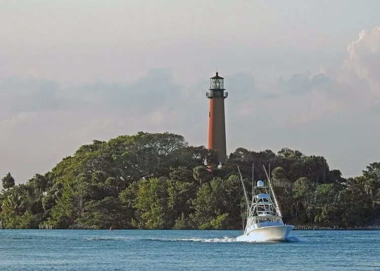 A boat sailing on the water near a lighthouse.