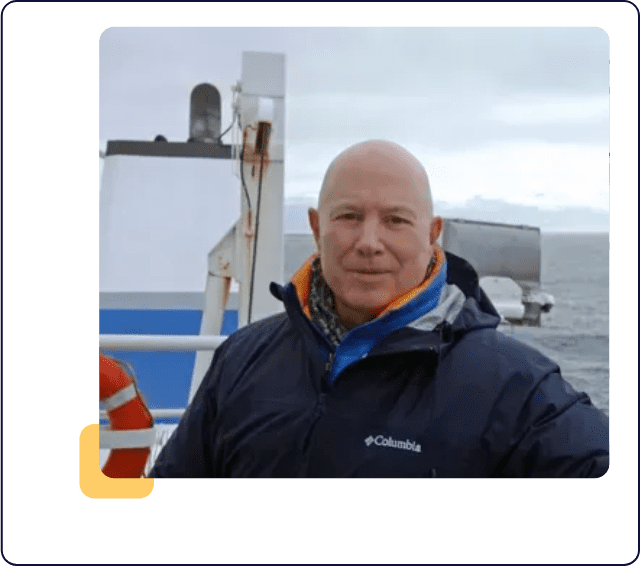 A man in a blue jacket standing on the deck of a boat.