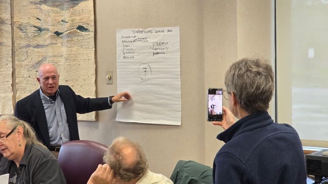 A man is pointing to a paper on the wall