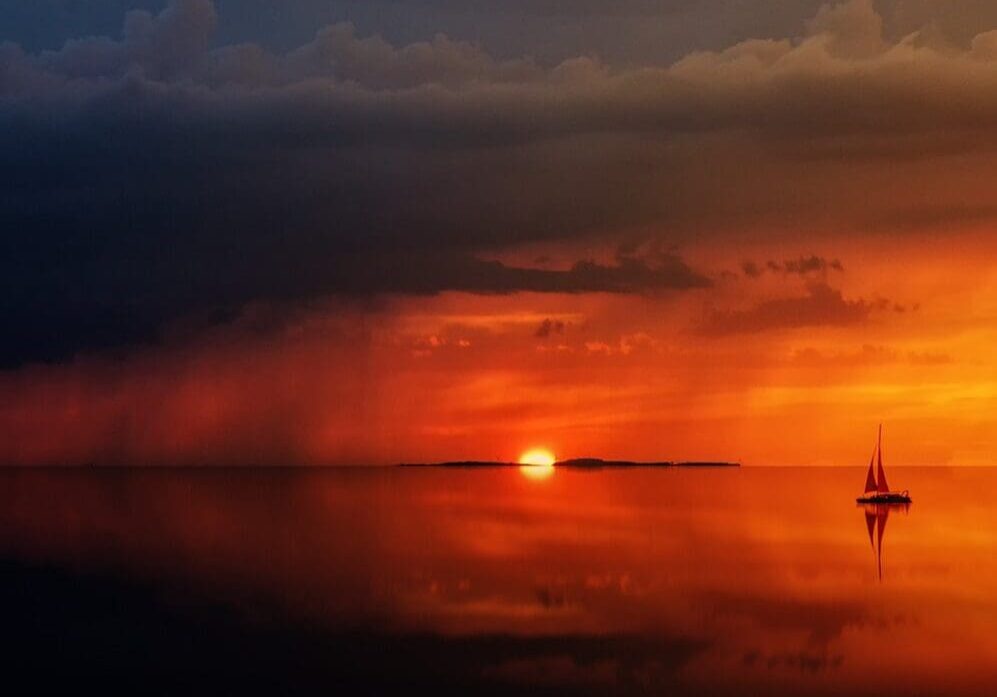 A sunset over the ocean with clouds in the sky.